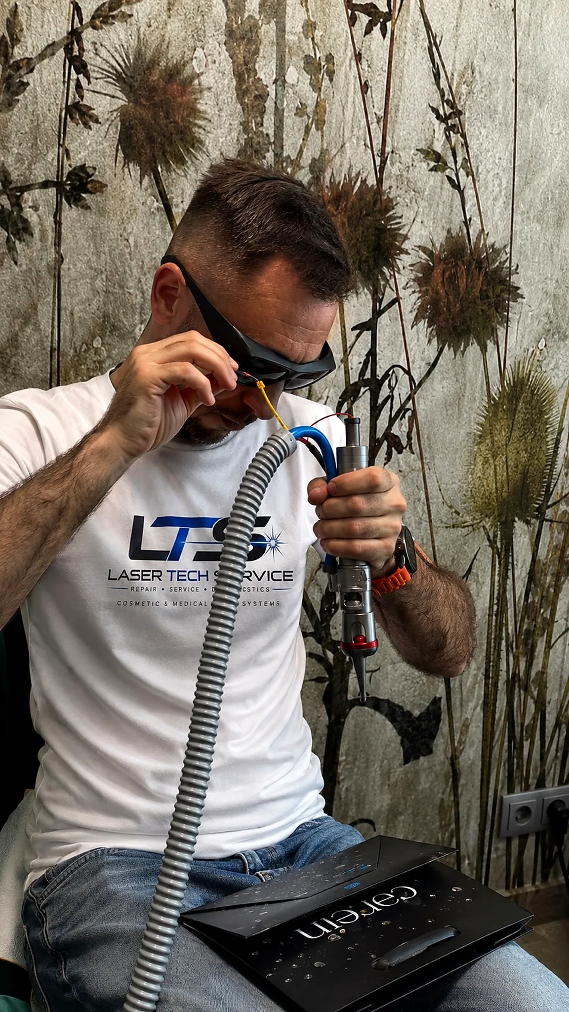 Specjalista w koszulce Laser Tech Service podczas pracy przy rozebranej głowicy Nd:YAG